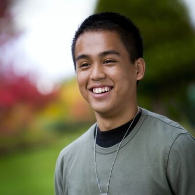 Asian teenage boy wearing necklance smiling
