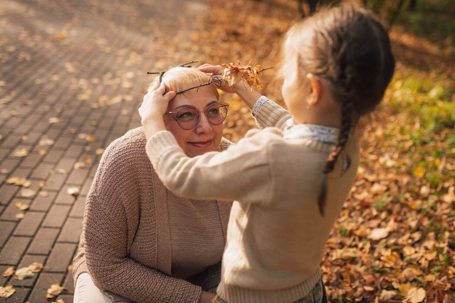 Woman kneeling in front of young girl in autumnal park