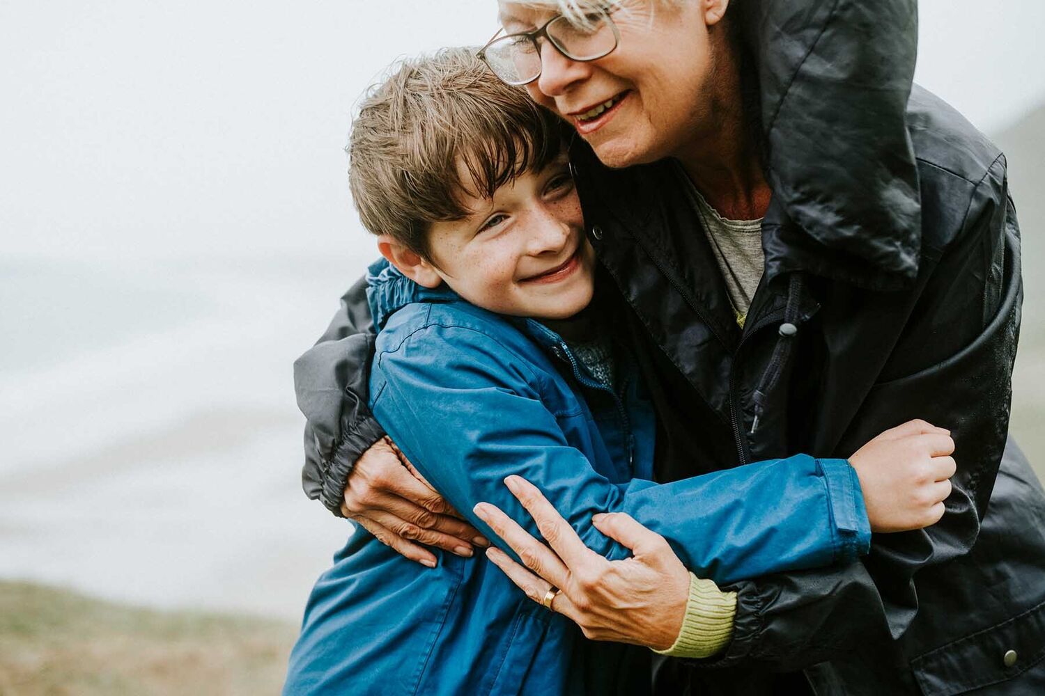 Young Boy And Grandma Hug In The Rain