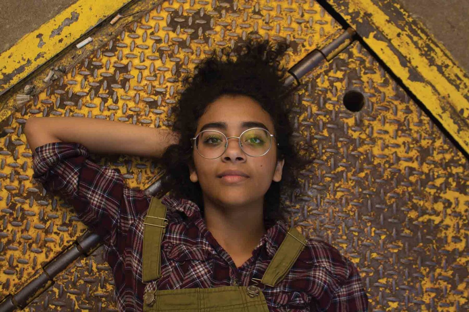 Young Woman With Big Glasses Lying On Metal Floor