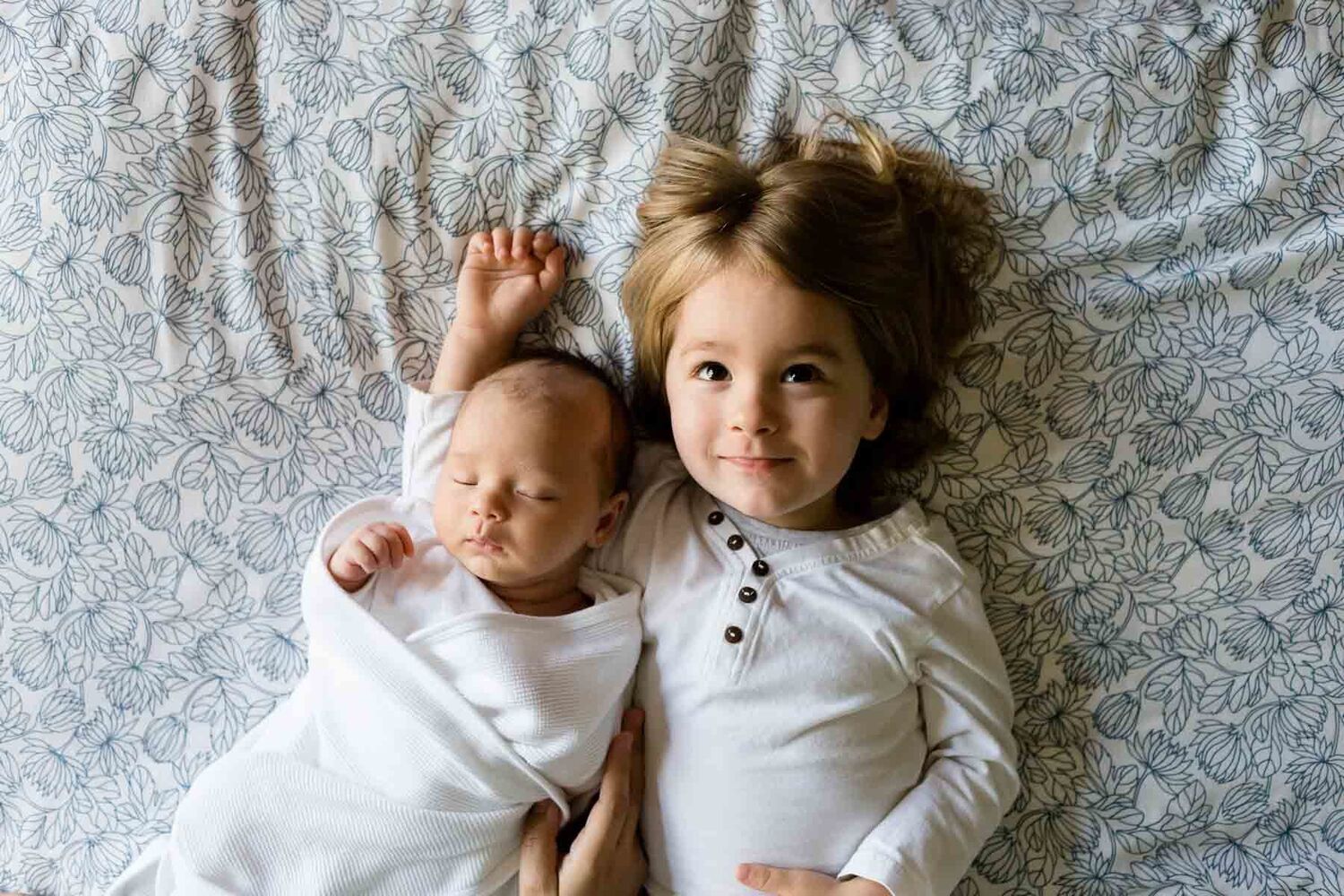 Baby And Toddler Brothers Lying On Bedsheet