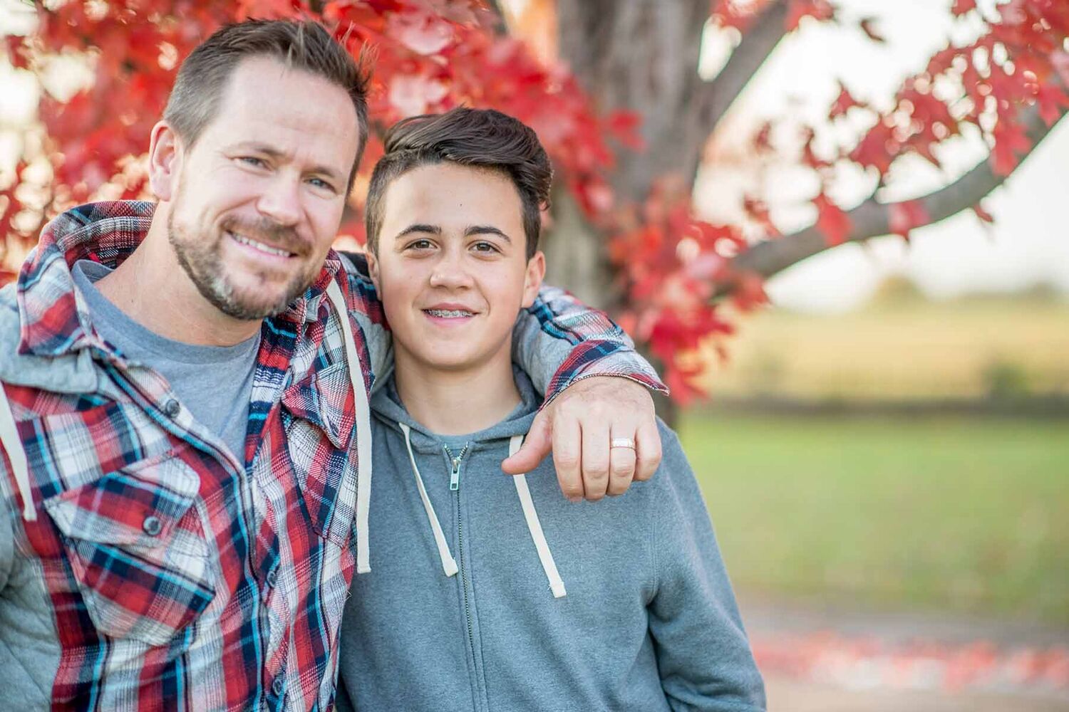 Father And Son Standing In Front Of A Red Tree