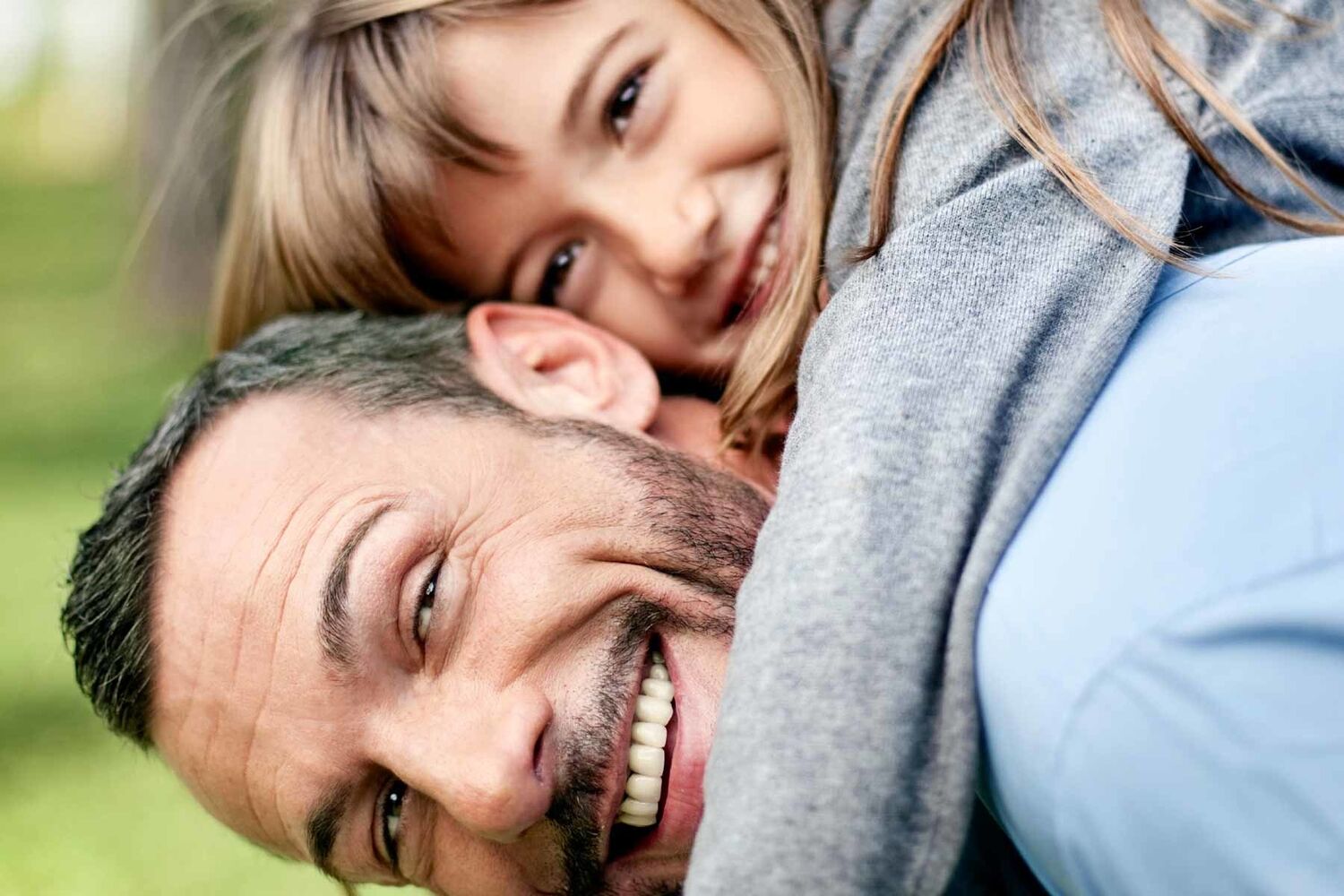 Man With Young Girl On Back Both Smiling At Camera