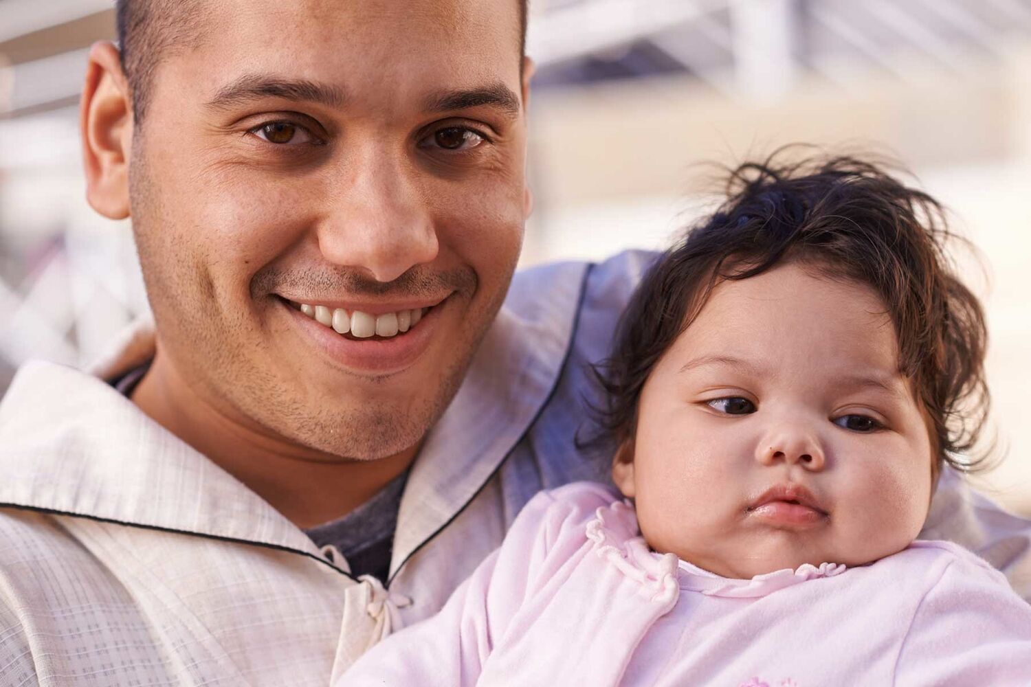 Father Holding Baby Girl With Chubby Cheeks Smiling Into Camera
