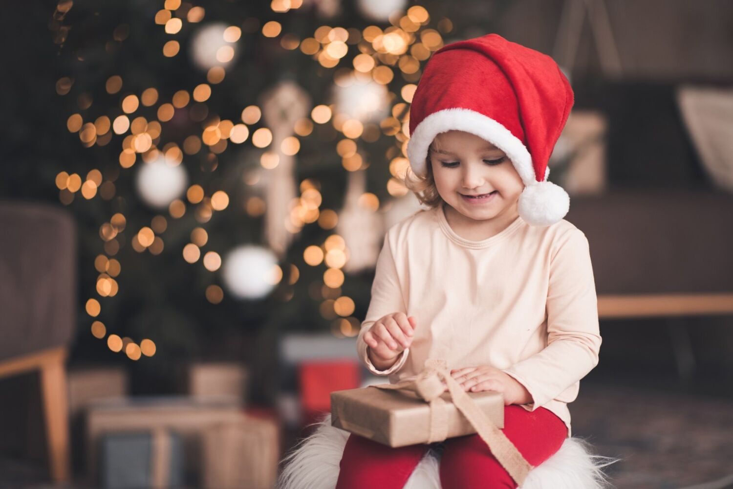 Smiling Baby Girl Wearing Santa Claus Hat And Pajamas Open Xmas Present Box Over Christmas Tree