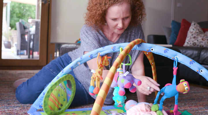 Foster Carer Kylie Looking At Baby On Play Mat