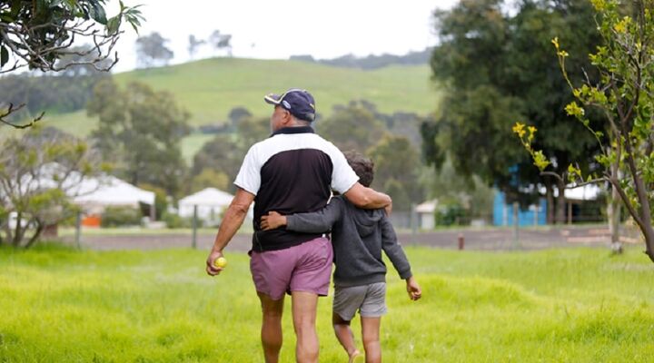 Aboriginal Father And Son Walking Across A Field