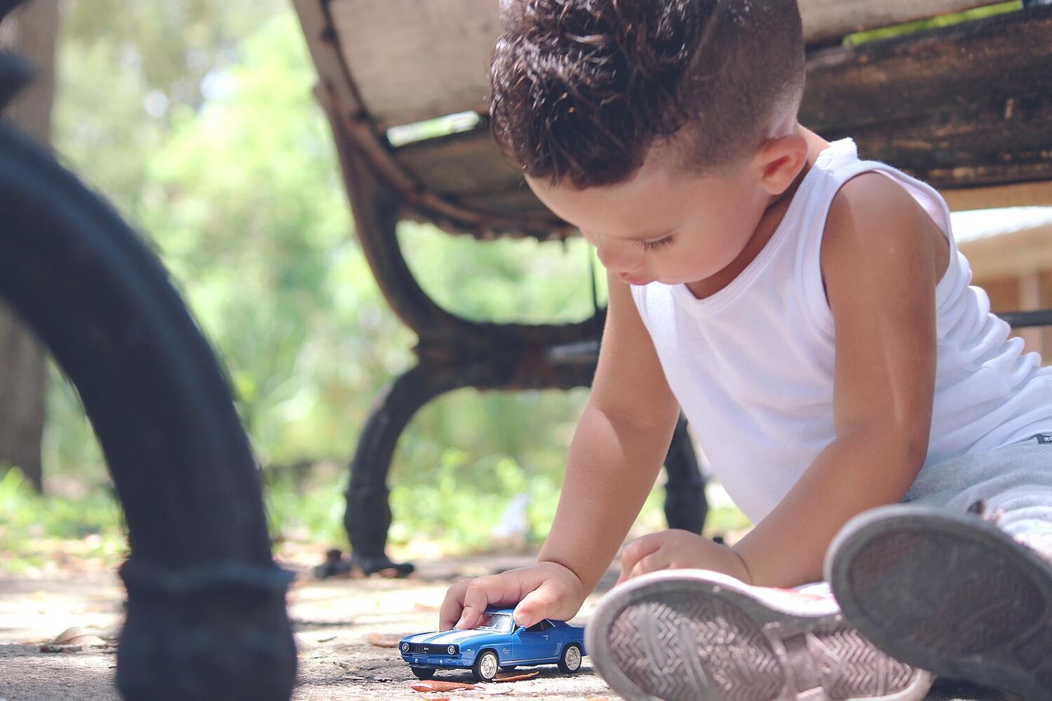 Young Boy Sitting On The Ground Playing With Toy Car