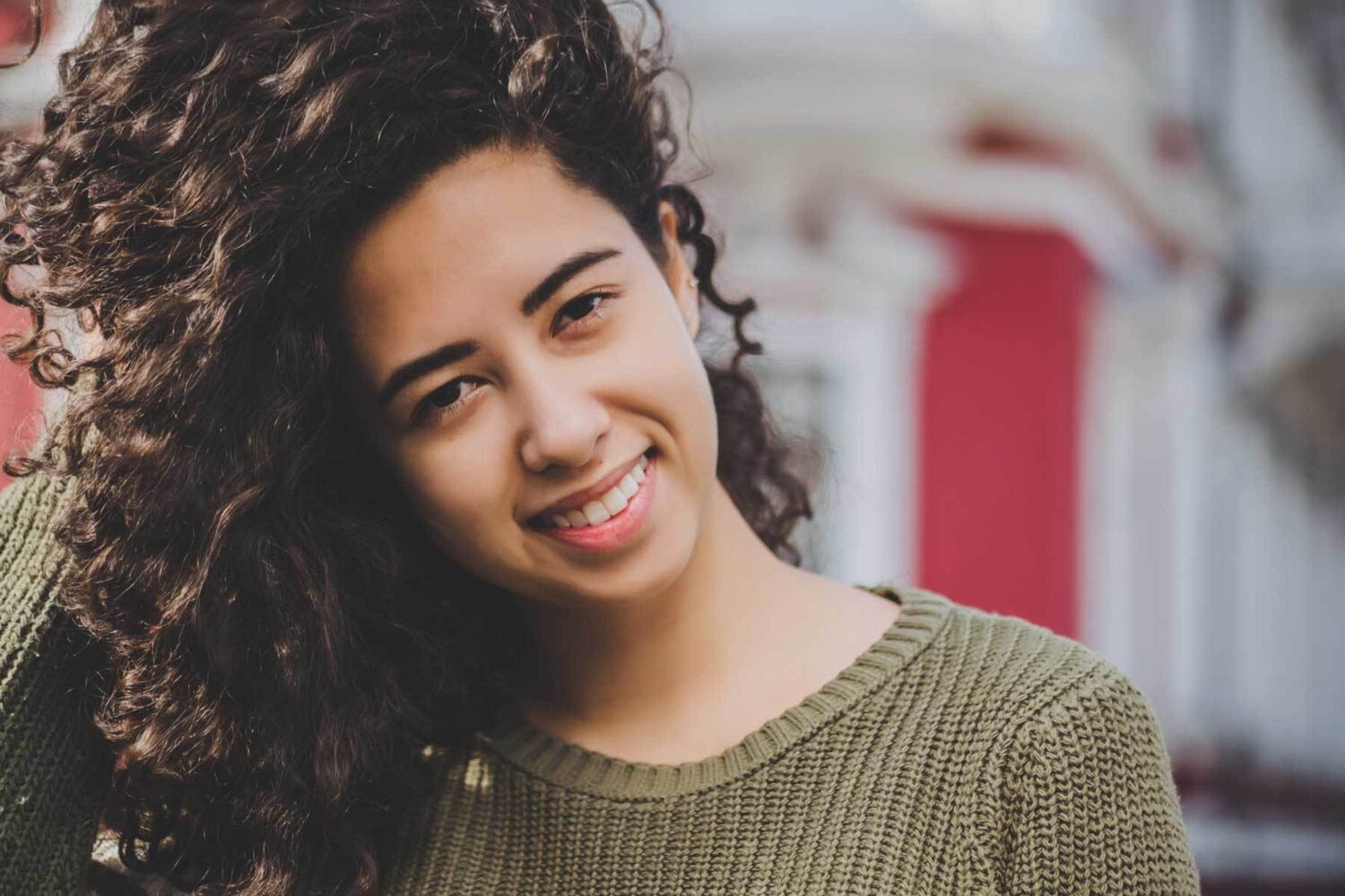 Young Girl With Curly Hair And Green Top Smiling