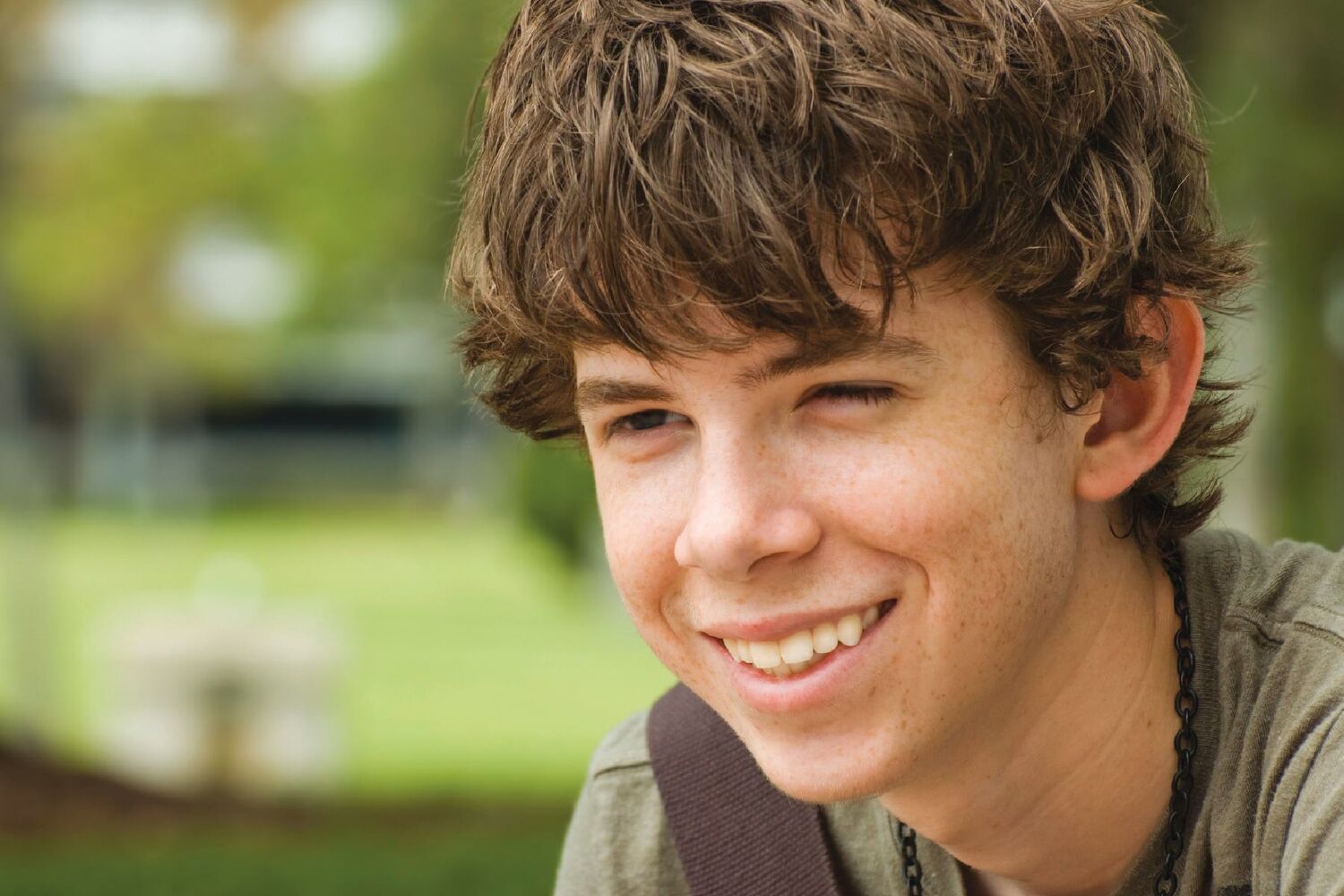 Teenage boy smiling wearing black chain