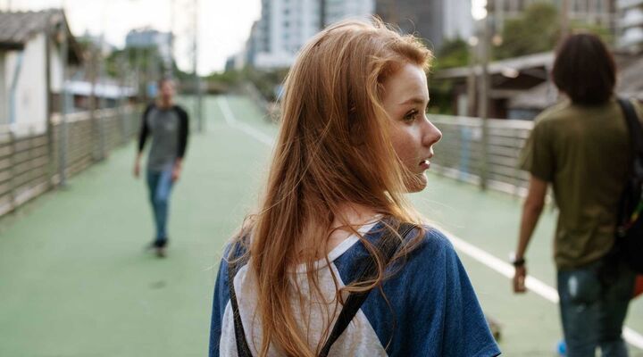 Young Woman With Long Red Hair And Backpack Looking Over Shoulder