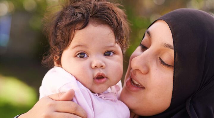 Woman Wearing Hijab Holding Baby Girl With Chubby Cheeks