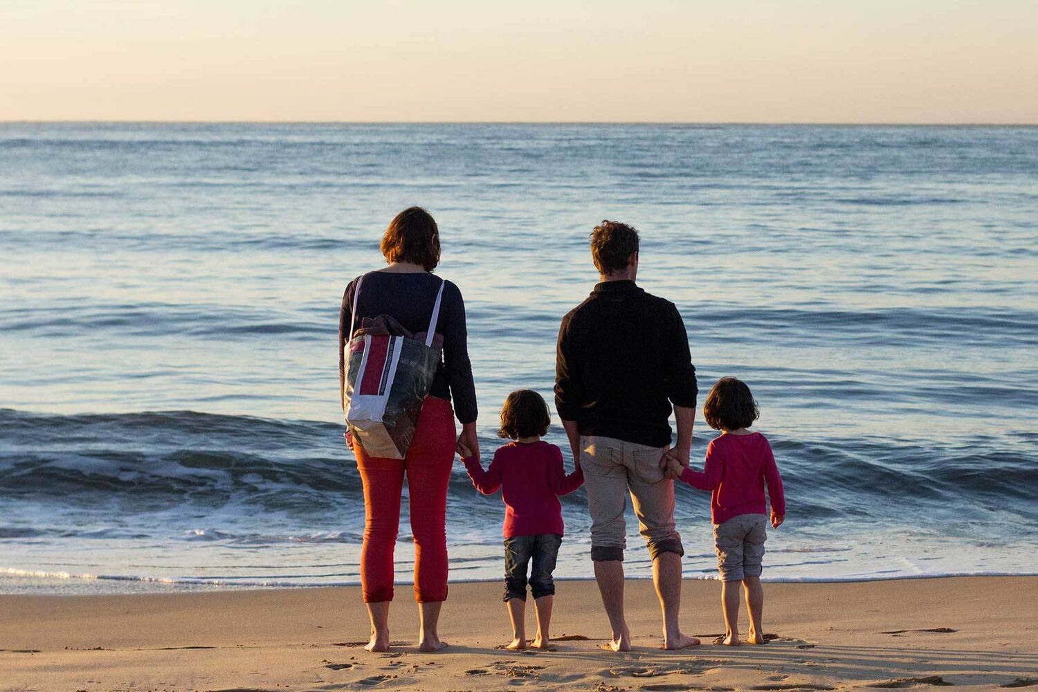 Family Standing On Beach Facing Away From Camera