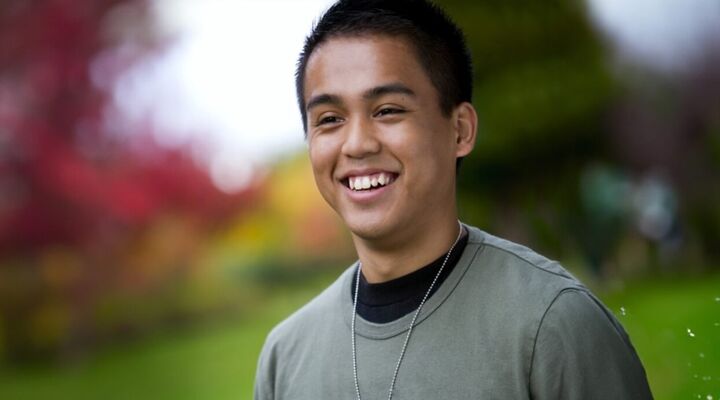 Asian teenage boy wearing necklance smiling