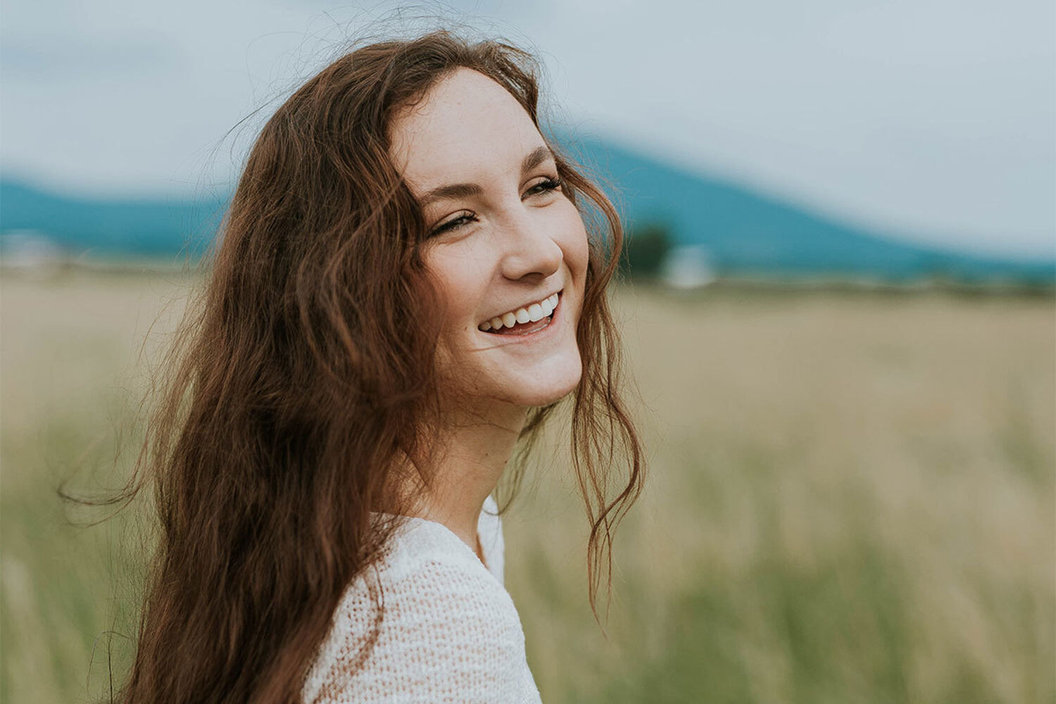 Young Woman In Field Smiling Into Distance