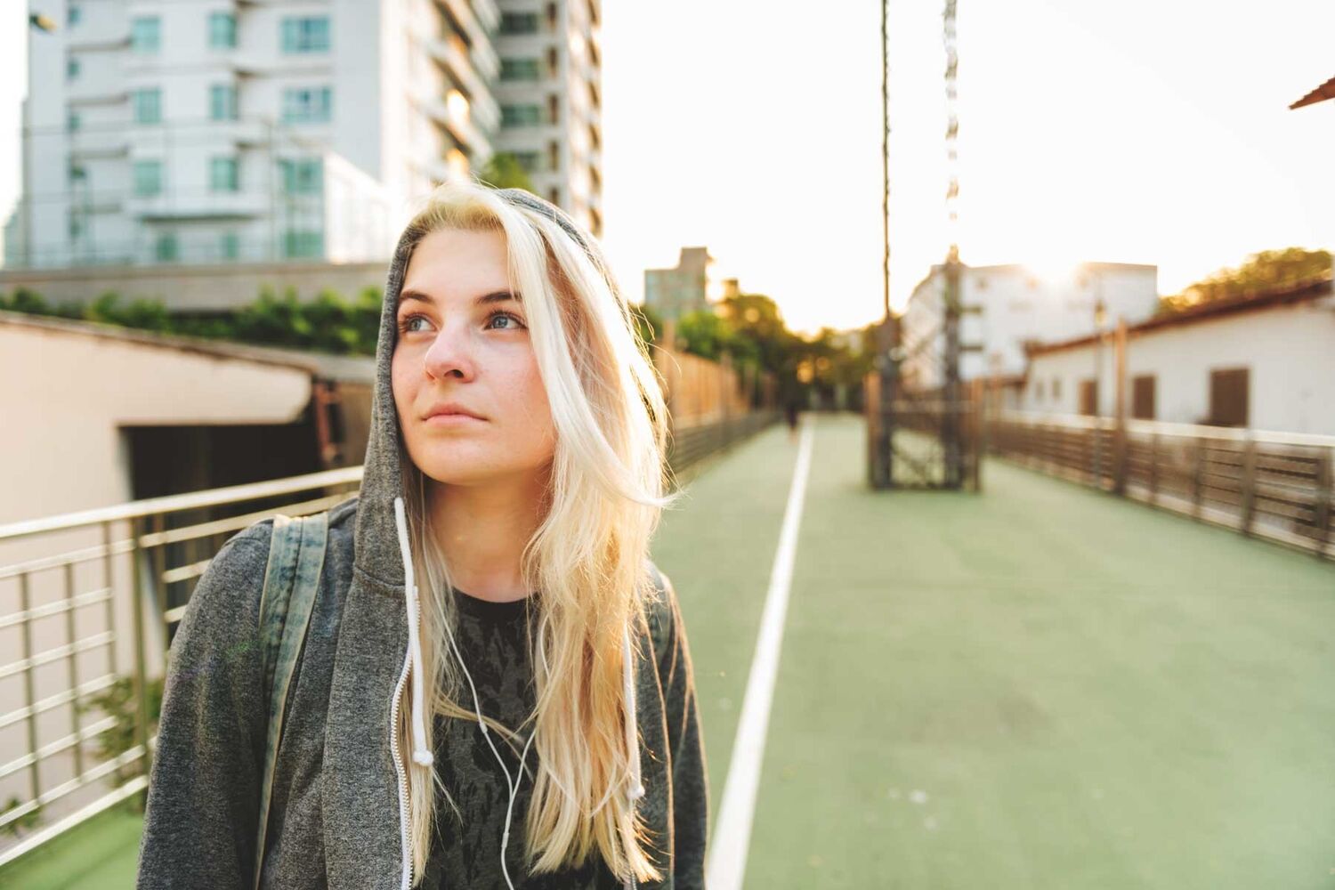 Young Woman With Blonde Hair In Grey Hoodie Looking Into Distance