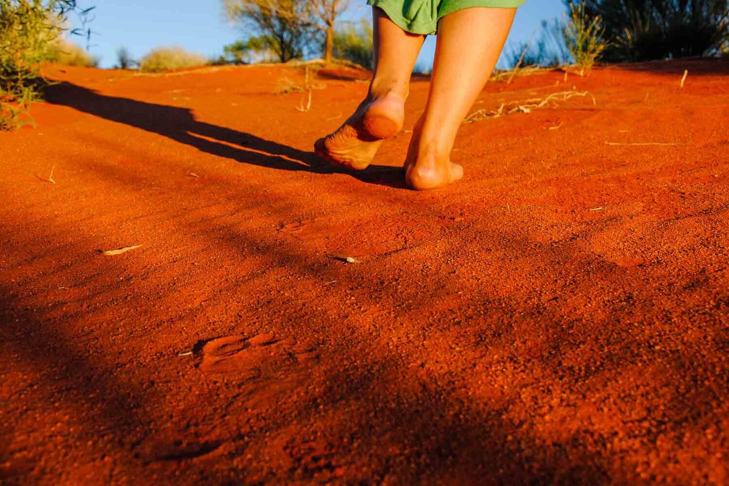 Feet Running In Red Earth Sand With Sliver Of Blue Horizon