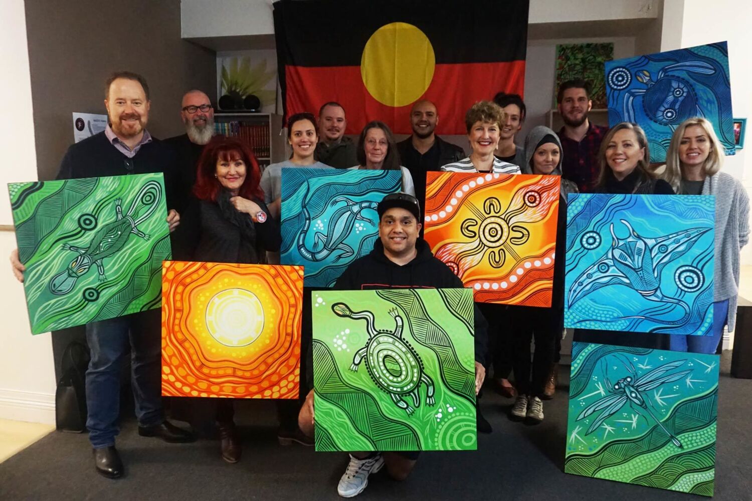 Aboriginal Artist Nathan Patterson With MacKillop's Out Of Home Care Team And Ceo Dr Robyn Miller Holding Artworks