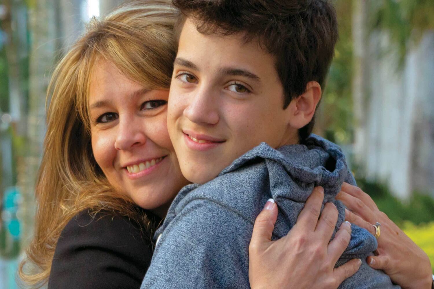 Happy Blonde Hair Woman Hugging Smiling Teenage Son