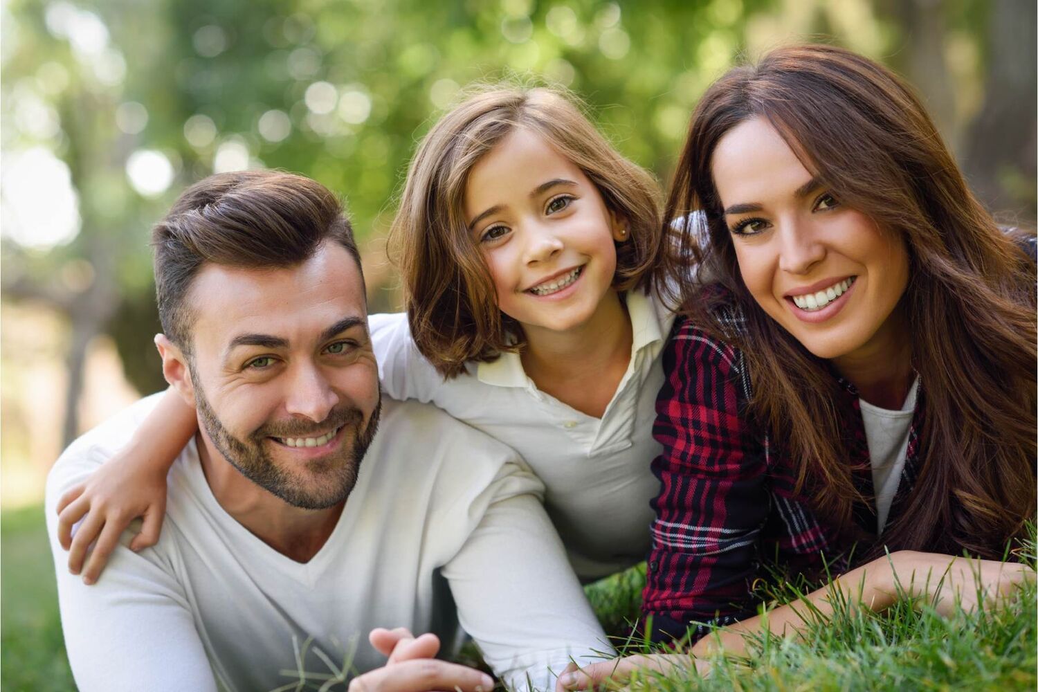 Family of three lying on grass smiling
