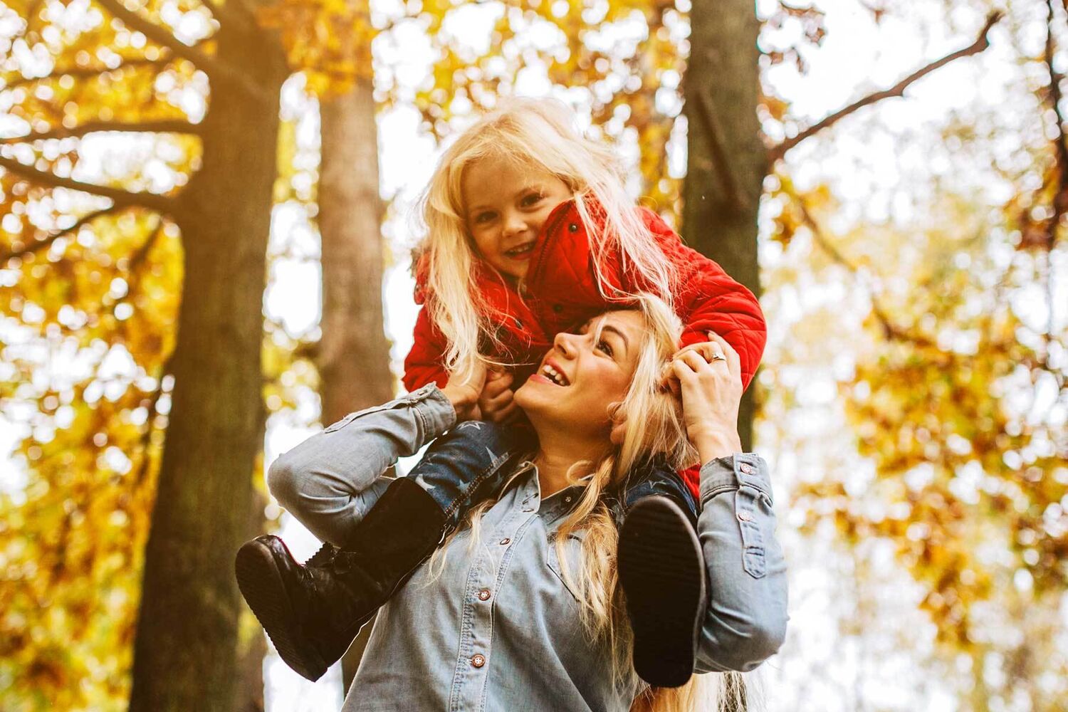 Woman With Young Girl On Shoulders In Autumnal Forest